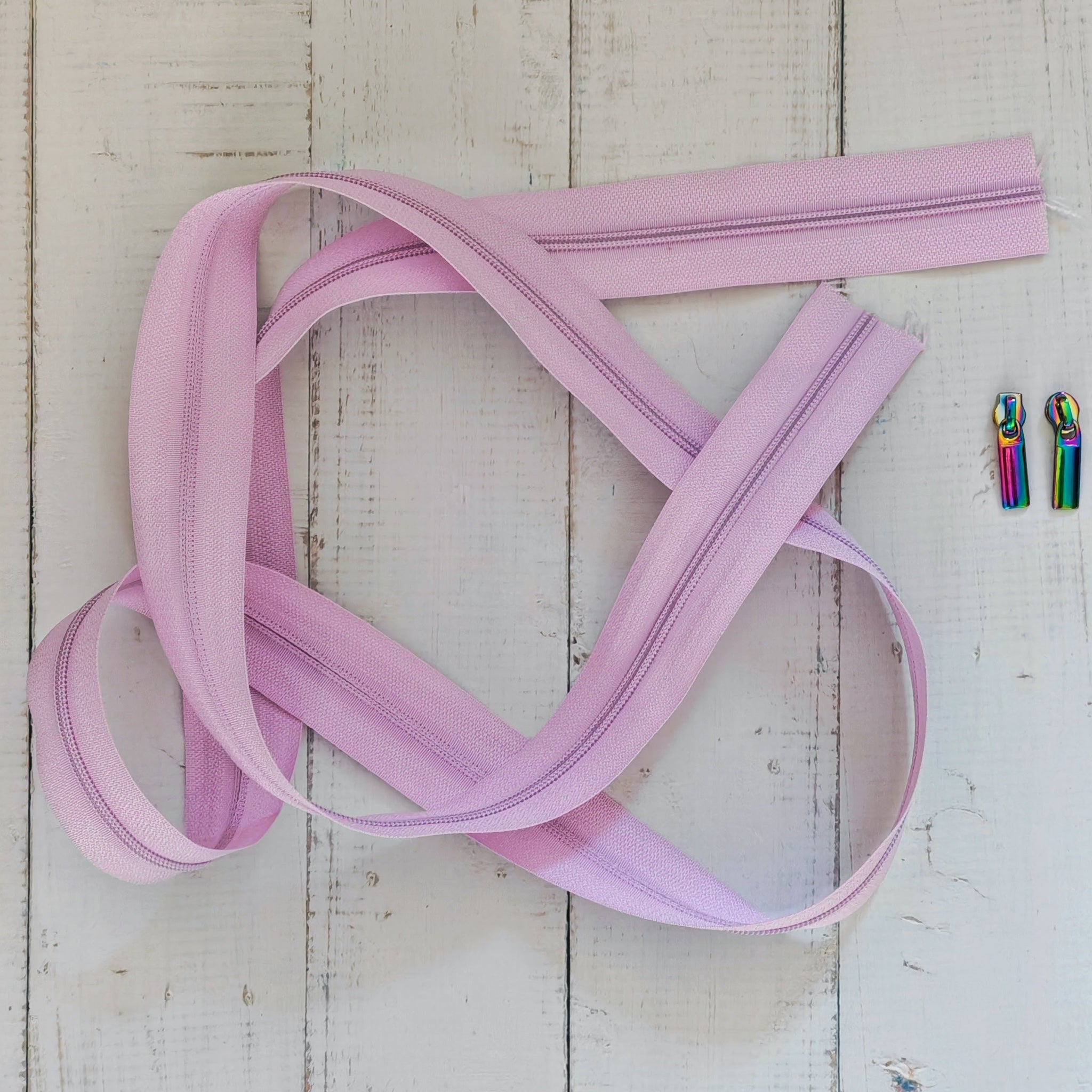 A lilac zipper,with two small metallic rainbow-colored zipper pulls