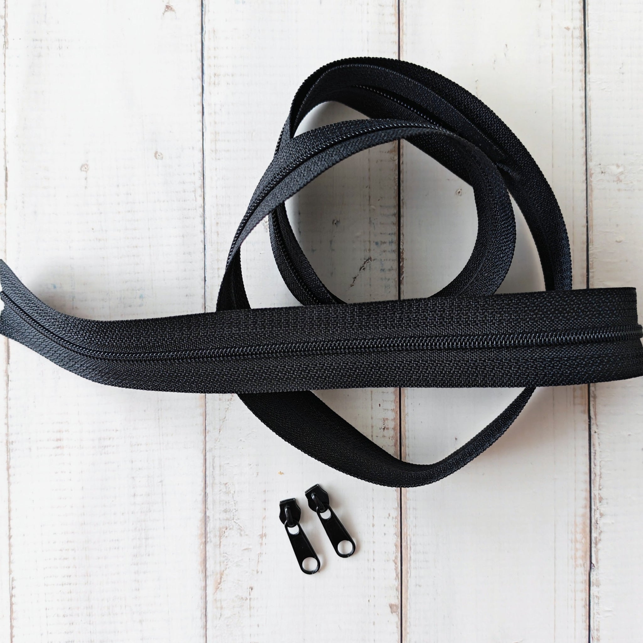 Black zipper and two black zipper pulls. 
