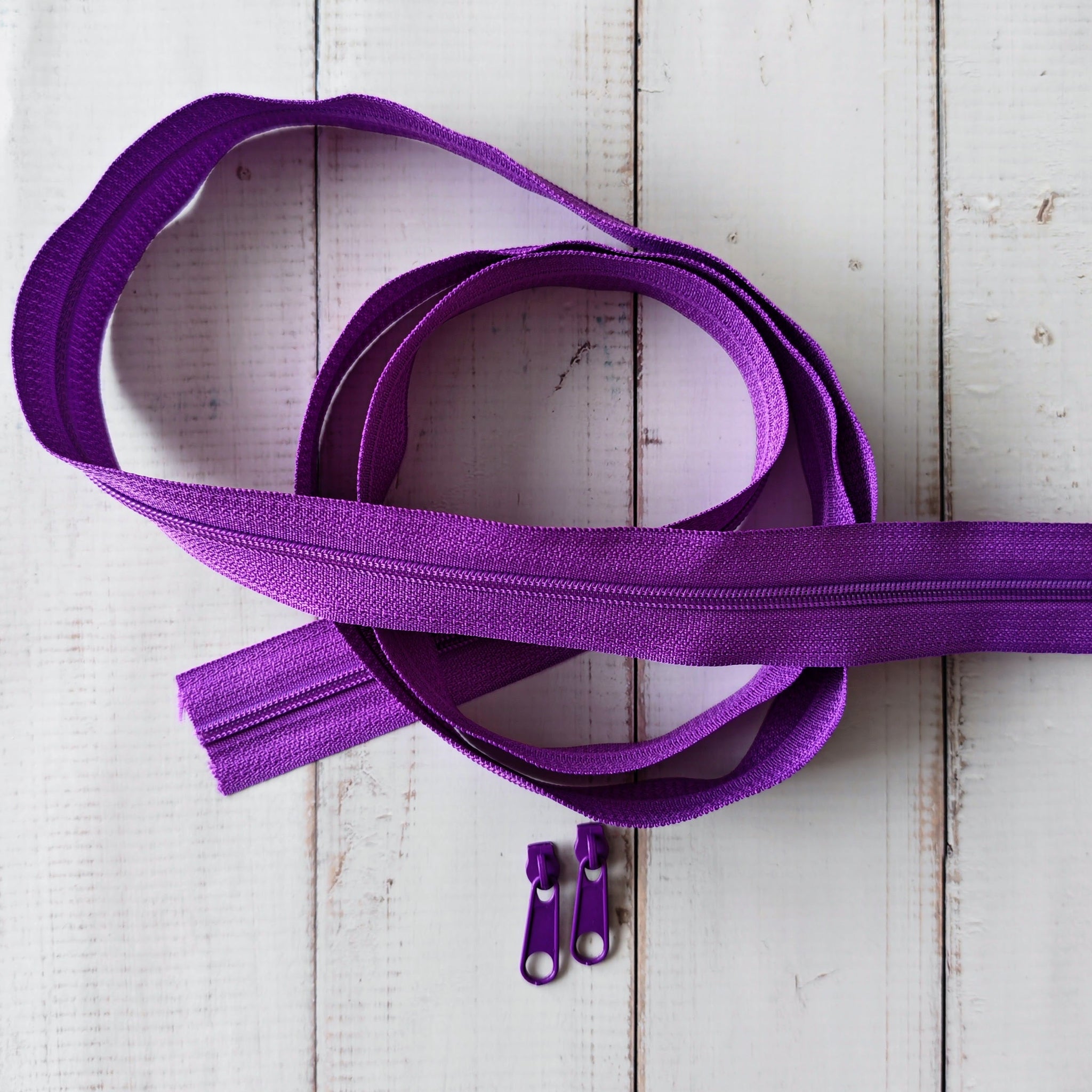 Purple zipper tape with two zipper pulls.