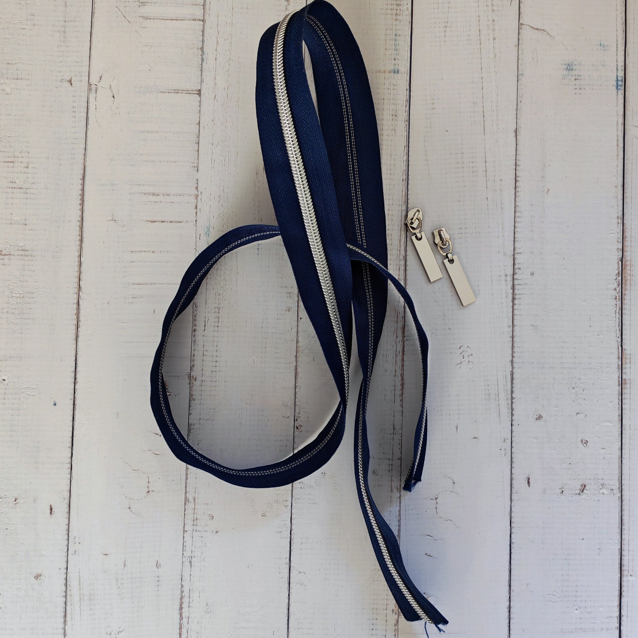 A navy blue zipper with silver metal teeth and matching silver zipper pulls.