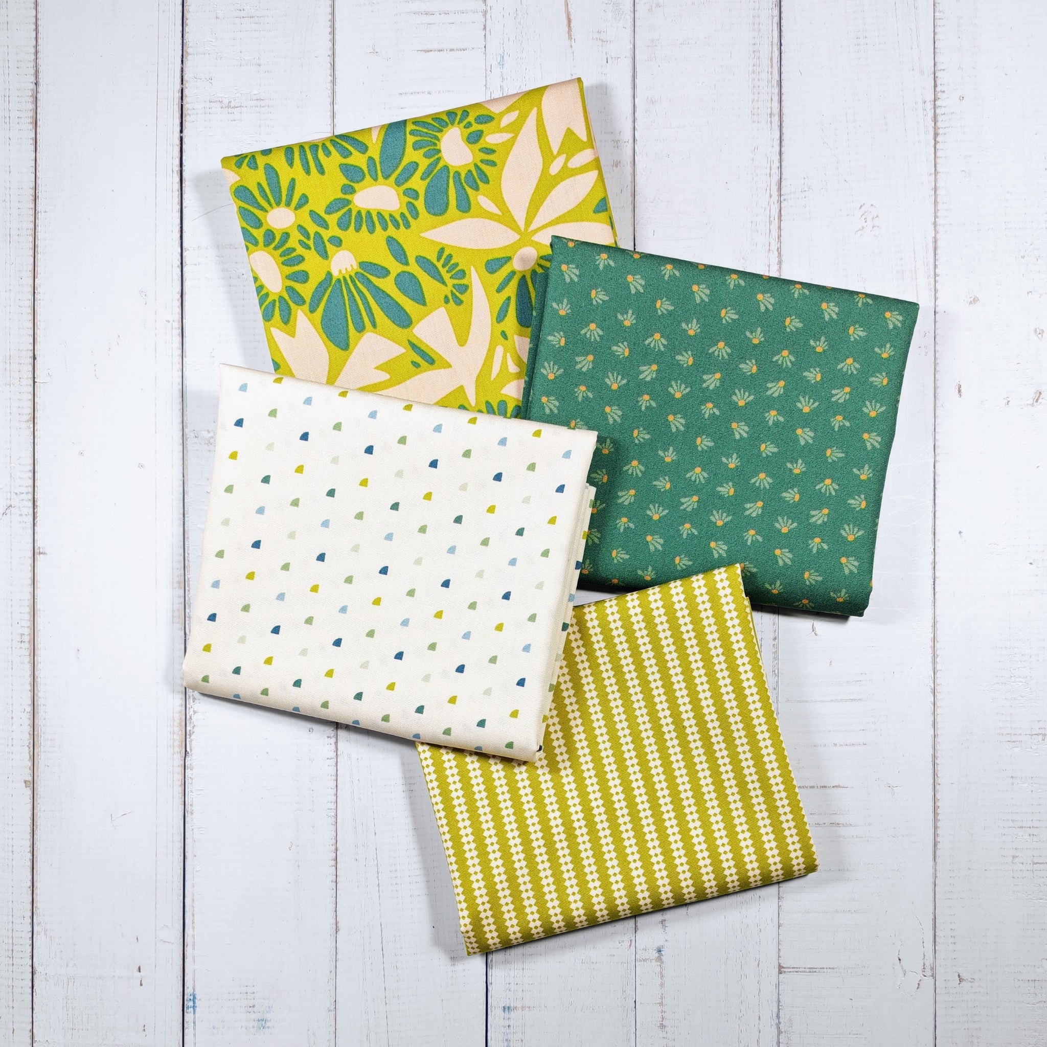 Four fabric fat quarters in yellows and greens with different patterns 