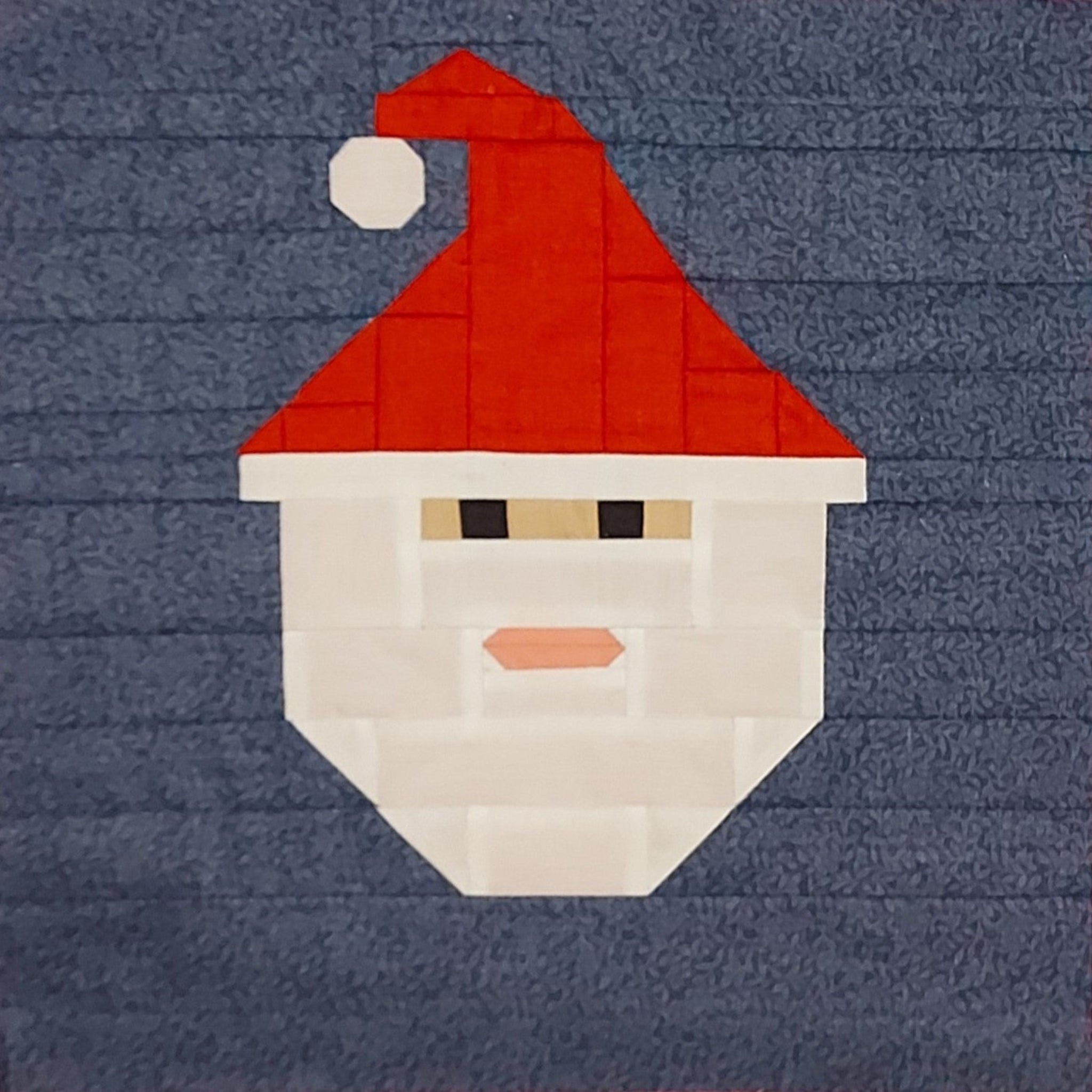 Quilt block with a Santa Claus face on a blue background