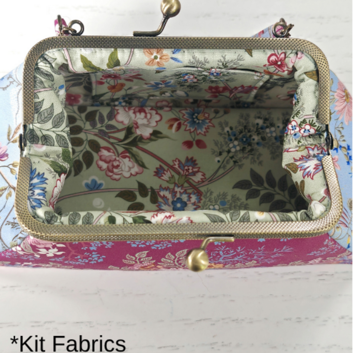 A rectangle kiss-lock handbag shown open to display its floral fabric lining and exterior. The bag features a pink floral pattern on the front, a multicolor floral print lining, and a gold-tone metal frame with a clasp.