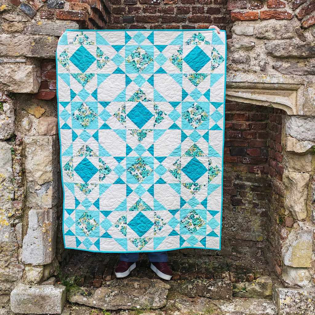 Aqua and white quilt draped over a stone archway.