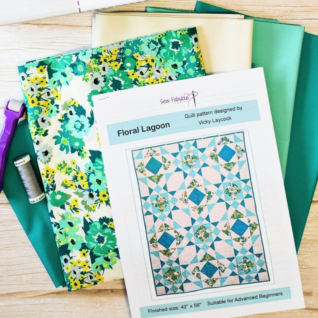 Quilt pattern titled 'Floral Lagoon' with fabric and sewing tools on a wooden surface.